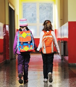 Happy two girls walking indoor at school hall